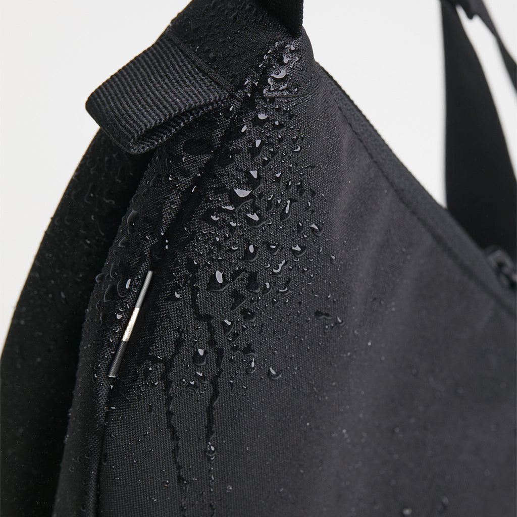 MOON BAG SMALL Tasche in black (Schwarz) als Detailaufnahme mit Wassertropfen.
