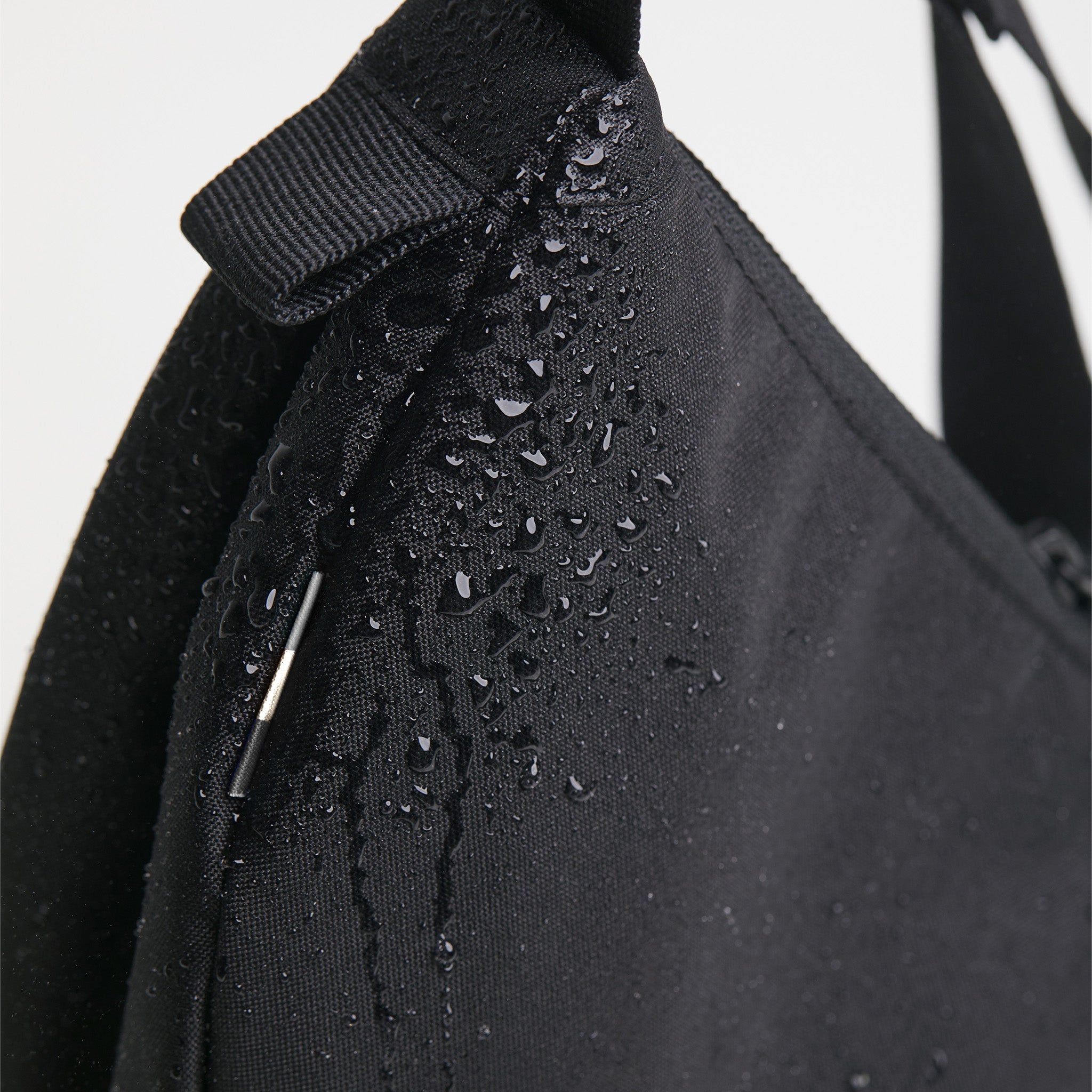 MOON BAG SMALL Tasche in black (Schwarz) als Detailaufnahme mit Wassertropfen.