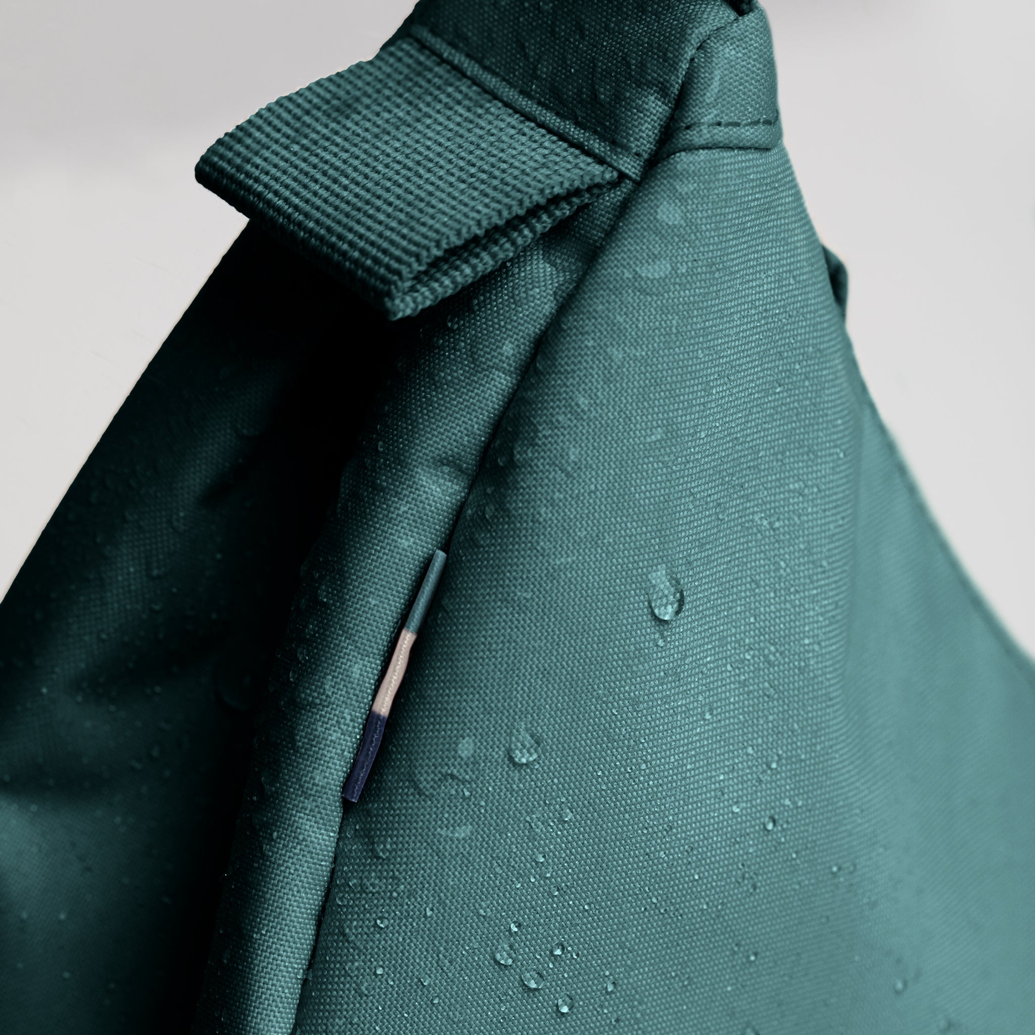 MOON BAG SMALL Tasche in sea teal (kühles Türkisgrün) als Detailaufnahme mit Wassertropfen.