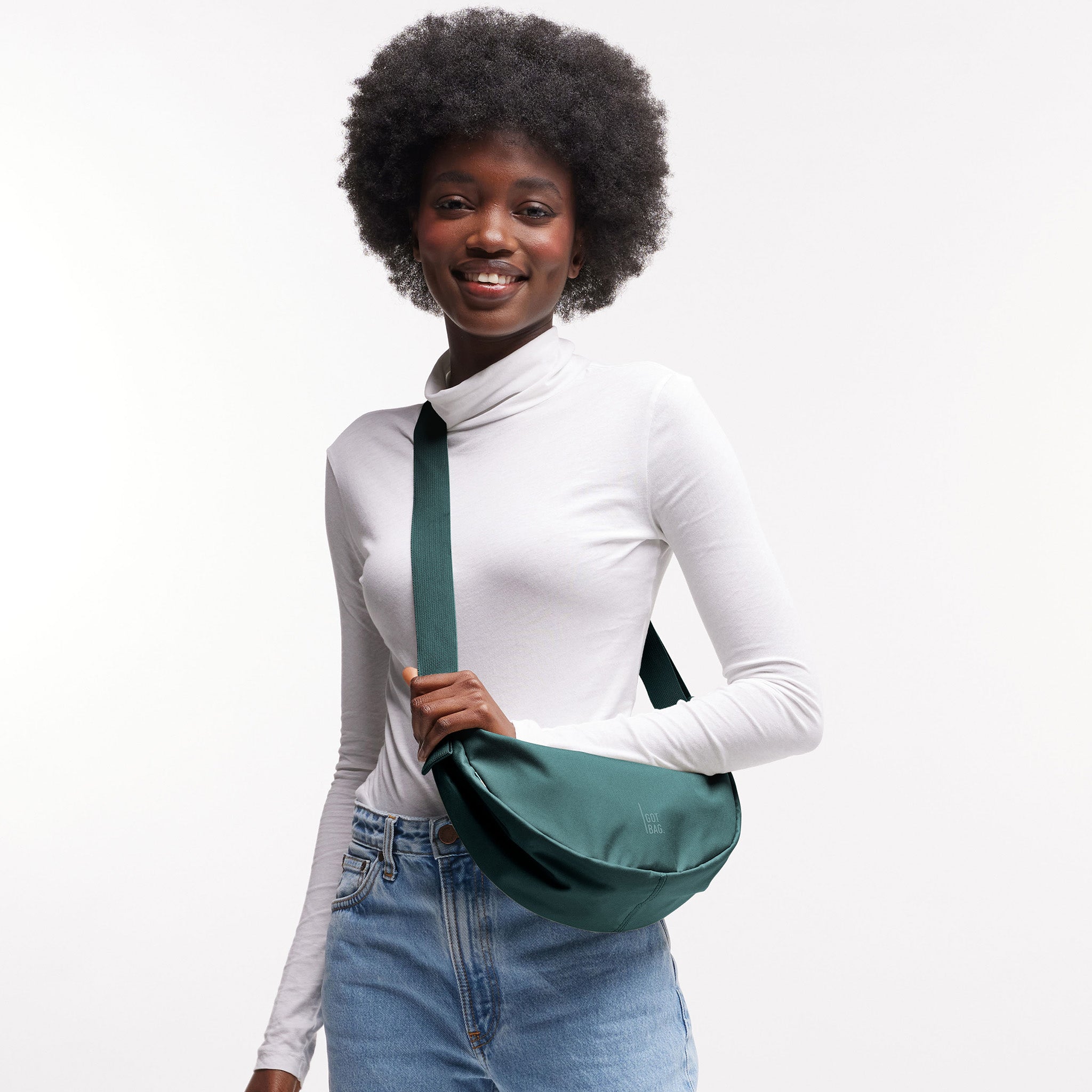 MOON BAG SMALL Tasche in sea teal (kühles Türkisgrün) von einer Frau crossbody getragen.