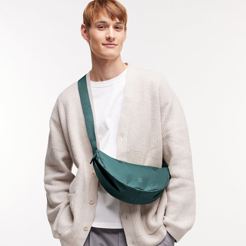 MOON BAG SMALL Tasche in sea teal (kühles Türkisgrün) von einem Mann crossbody getragen.
