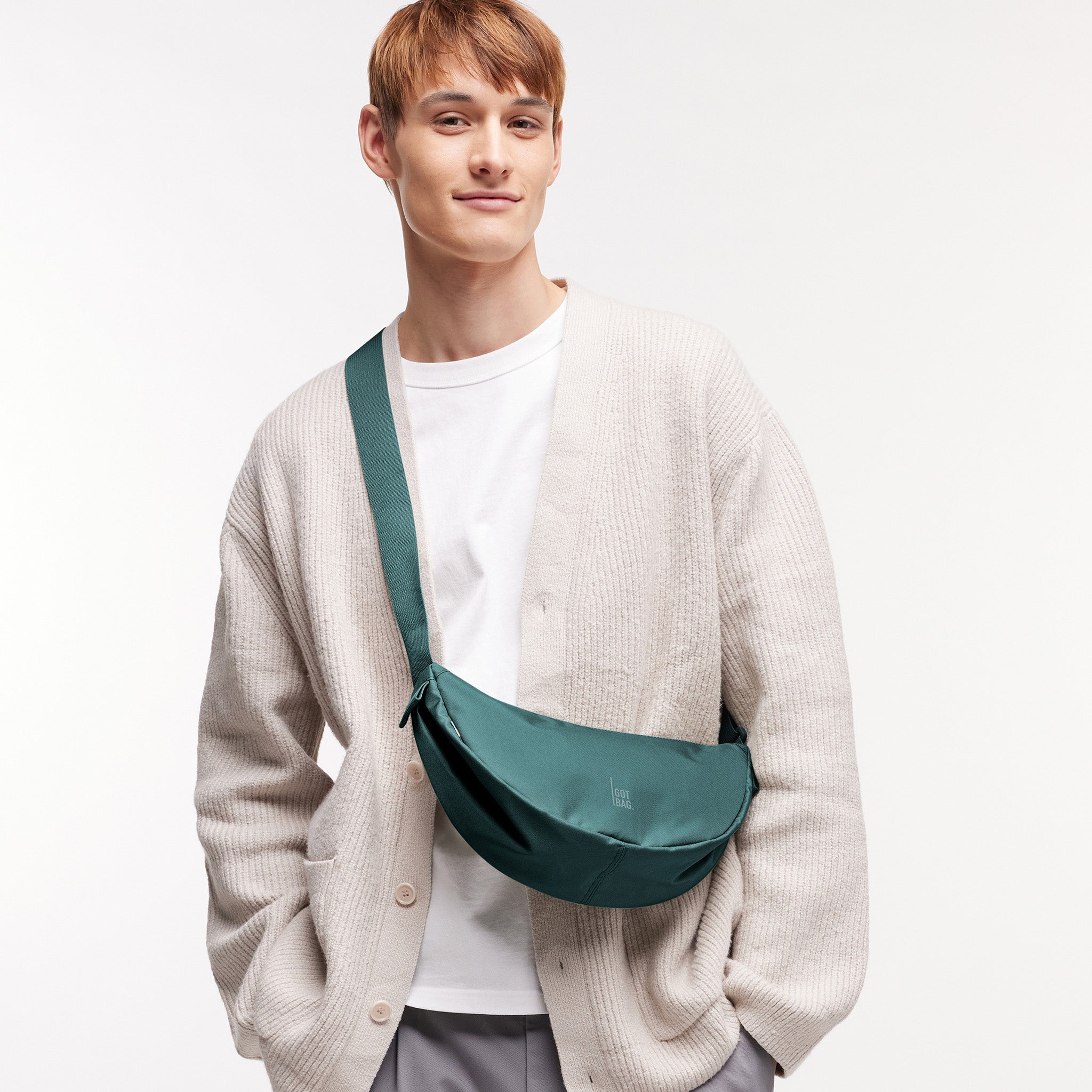 MOON BAG SMALL Tasche in sea teal (kühles Türkisgrün) von einem Mann crossbody getragen.