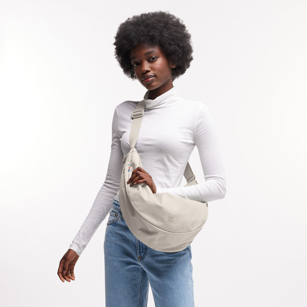 MOON BAG LARGE Tasche in soft shell (warmes Cremeweiß) von einer Frau crossbody getragen.