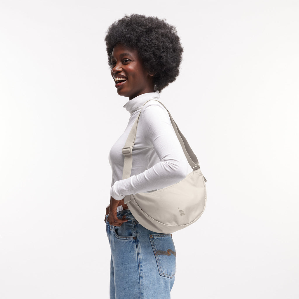 MOON BAG SMALL Tasche in soft shell (warmes Cremeweiß) von einer Frau crossbody getragen.