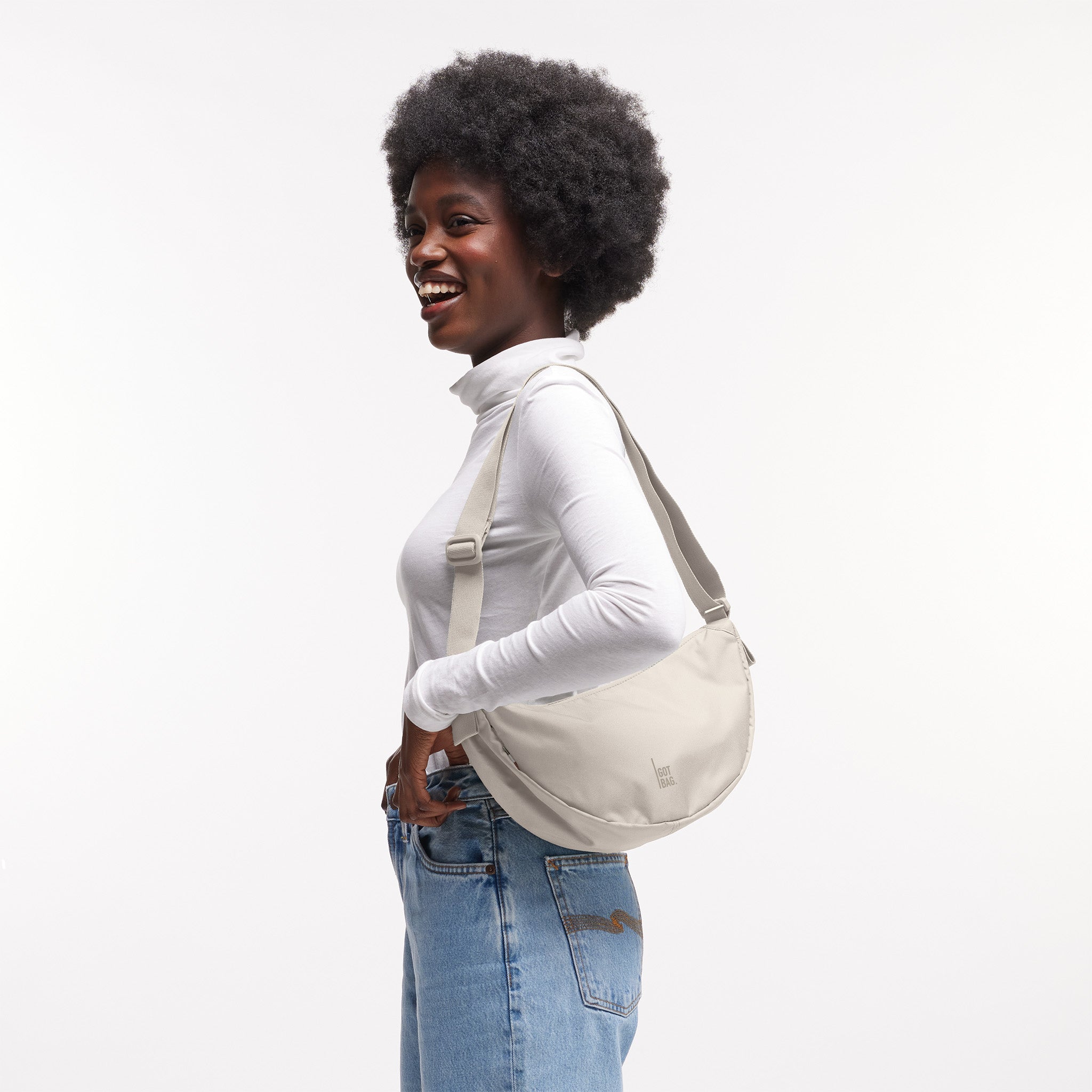 MOON BAG SMALL Tasche in soft shell (warmes Cremeweiß) von einer Frau crossbody getragen.
