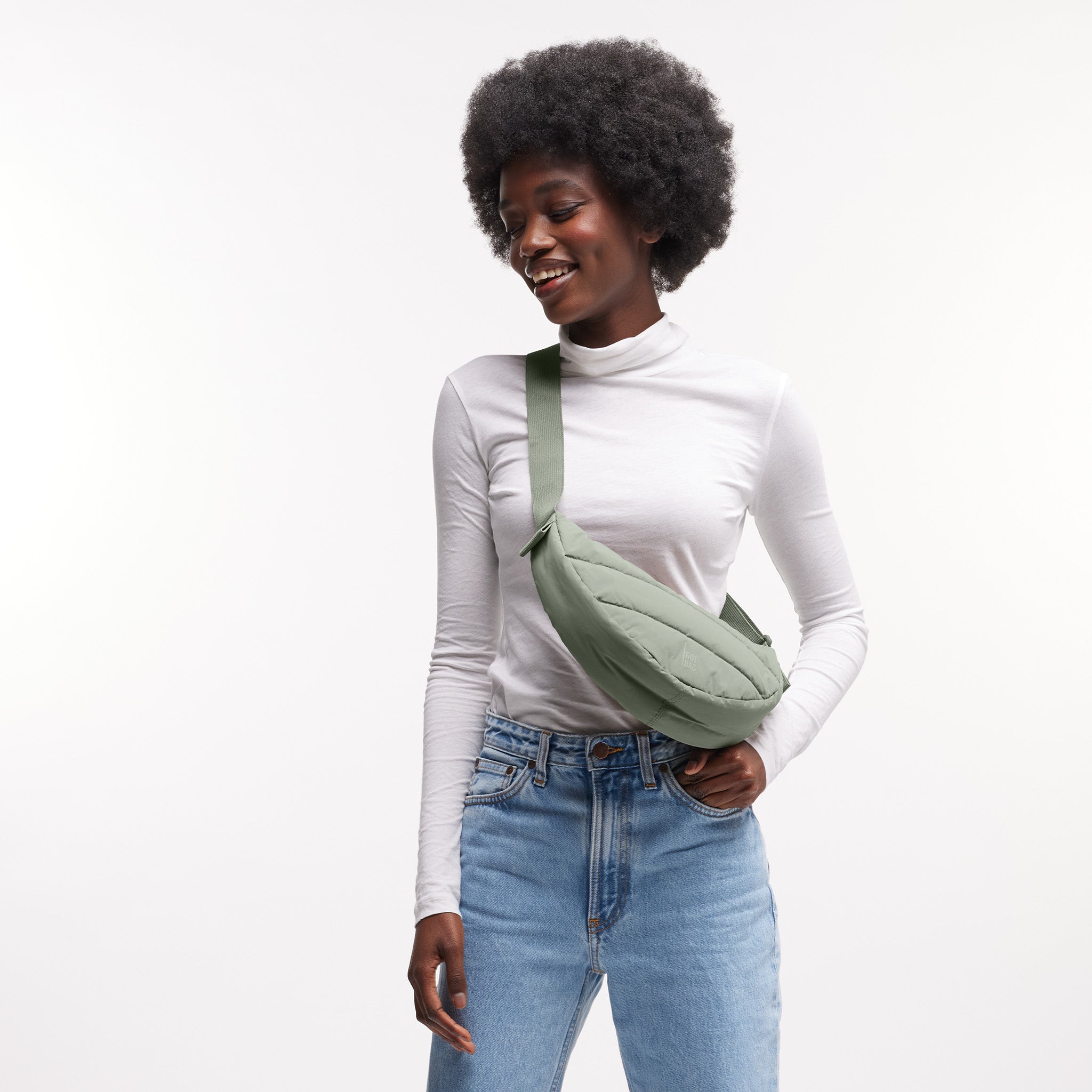 PUFFER MOON BAG SMALL Tasche in bass (Salbeigrün) von einer Frau crossbody getragen.