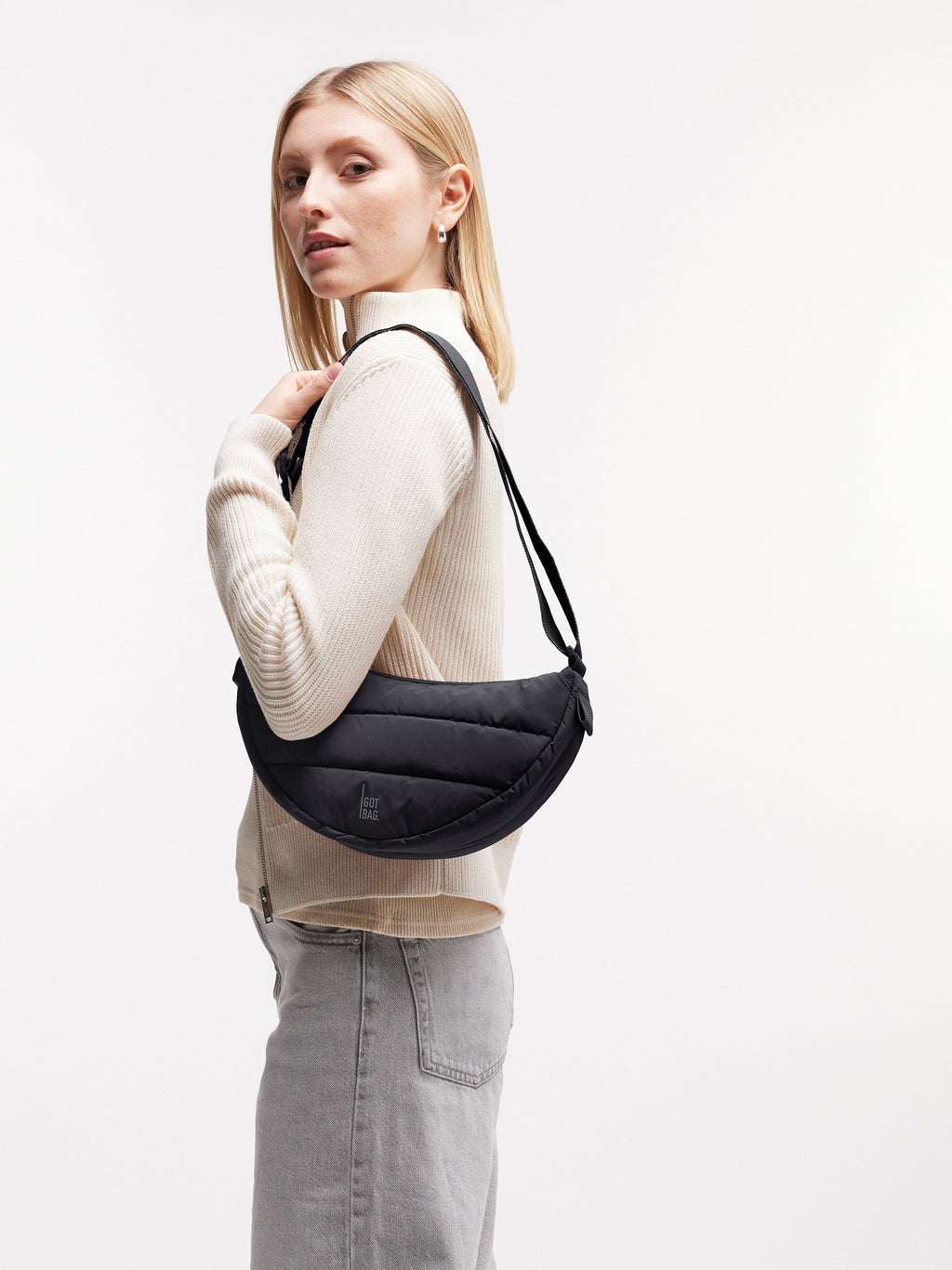 PUFFER MOON BAG SMALL Tasche in black (Schwarz) von einer Frau über der Schulter getragen.