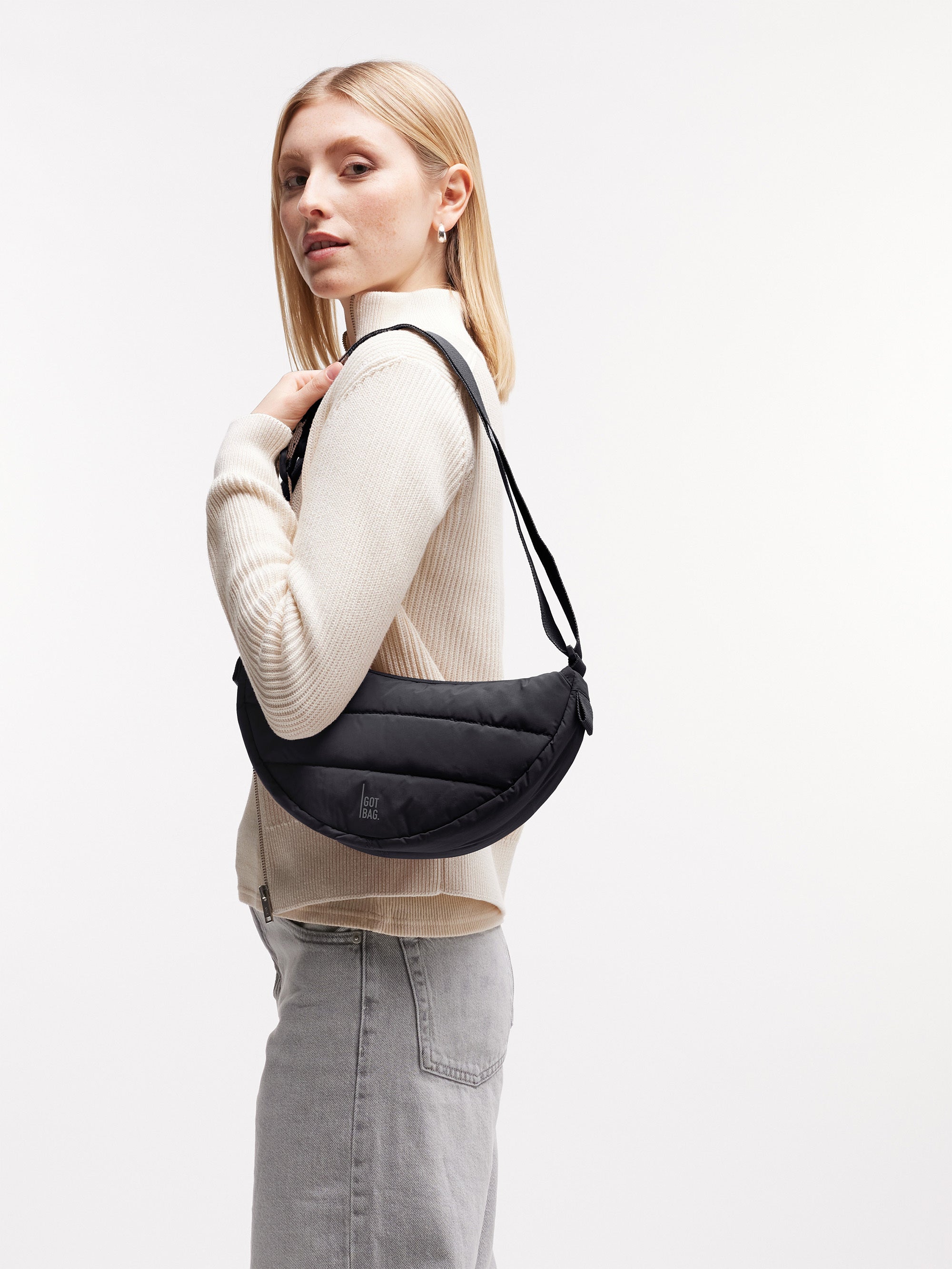 PUFFER MOON BAG SMALL Tasche in black (Schwarz) von einer Frau über der Schulter getragen.