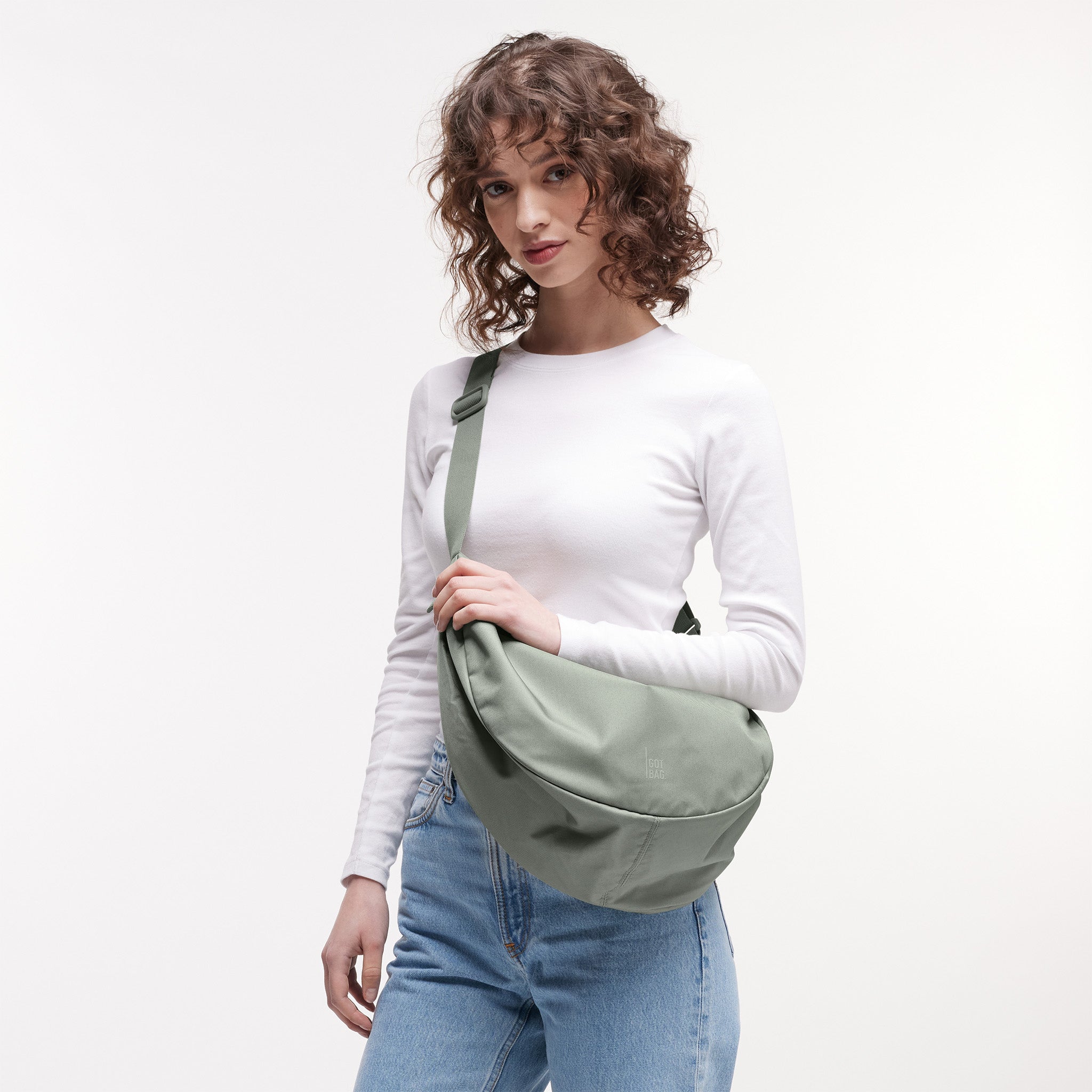 MOON BAG LARGE Tasche in bass (Salbeigrün) von einer Frau crossbody getragen.