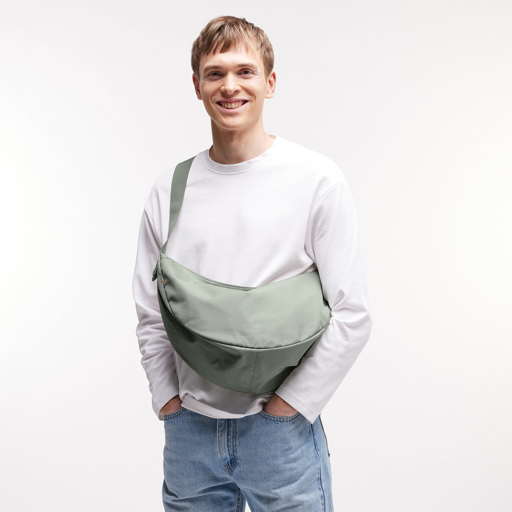 MOON BAG LARGE Tasche in bass (Salbeigrün) von einem Mann crossbody getragen.