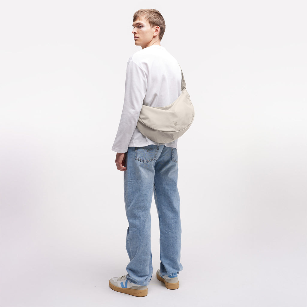 MOON BAG LARGE Tasche in soft shell (warmes Cremeweiß) von einem Mann crossbody getragen.