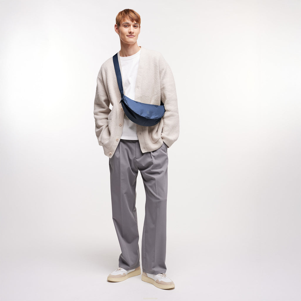 MOON BAG SMALL Tasche in deep ocean (dunkles Marineblau) von einem Mann crossbody getragen.