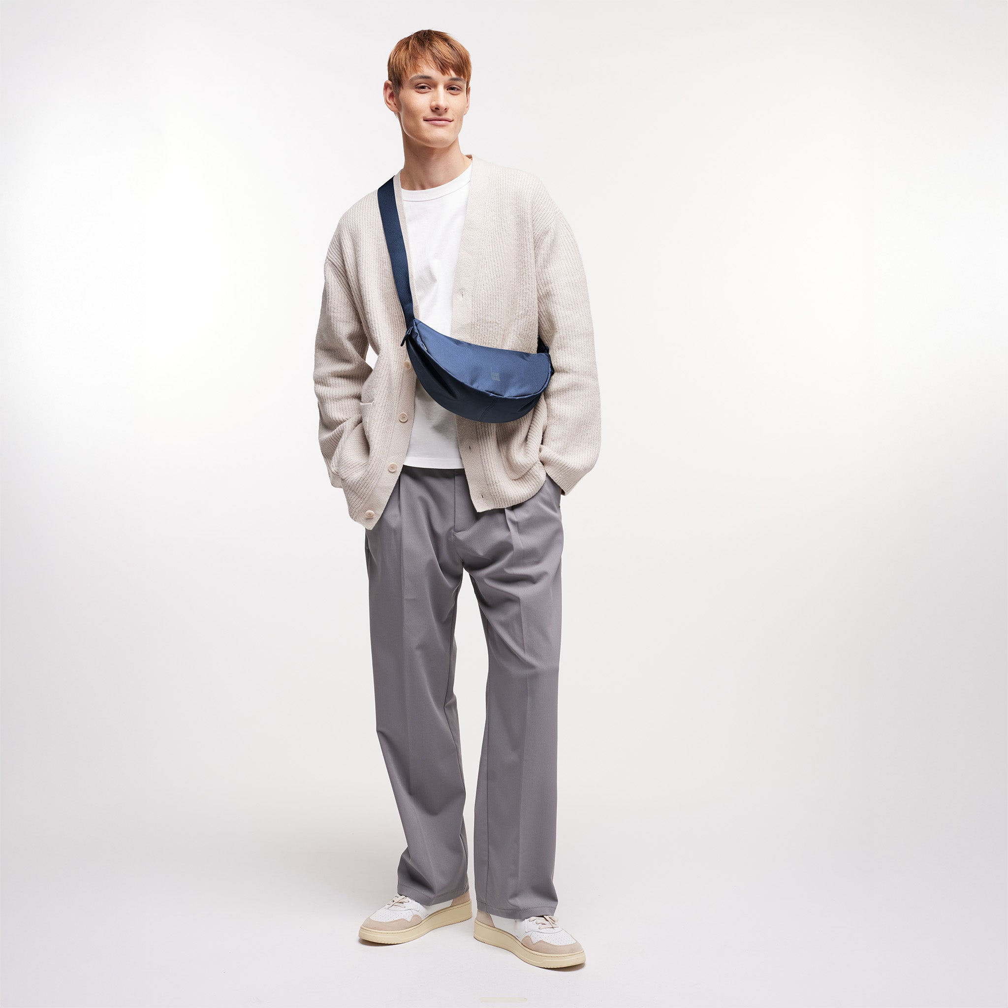MOON BAG SMALL Tasche in deep ocean (dunkles Marineblau) von einem Mann crossbody getragen.