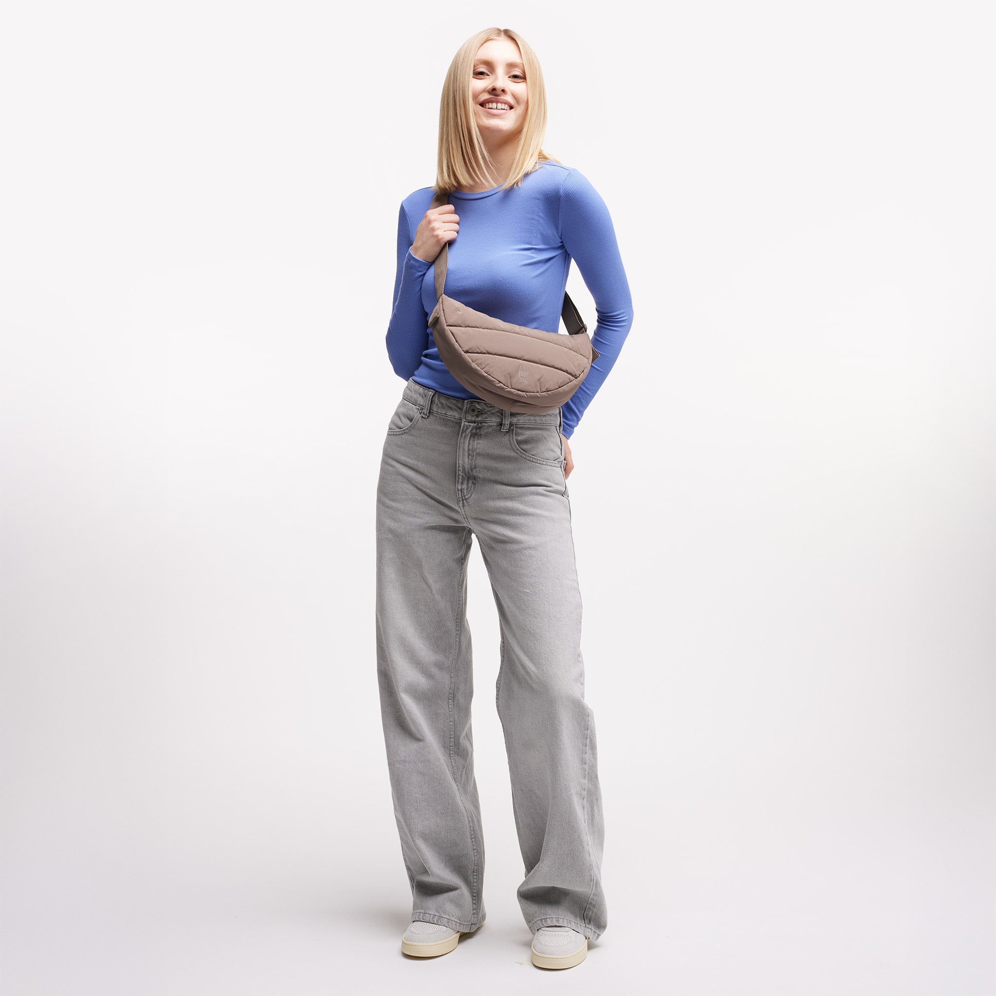 PUFFER MOON BAG SMALL Tasche in oyster (klassisches Taupe-Braun) von einer Frau crossbody getragen.