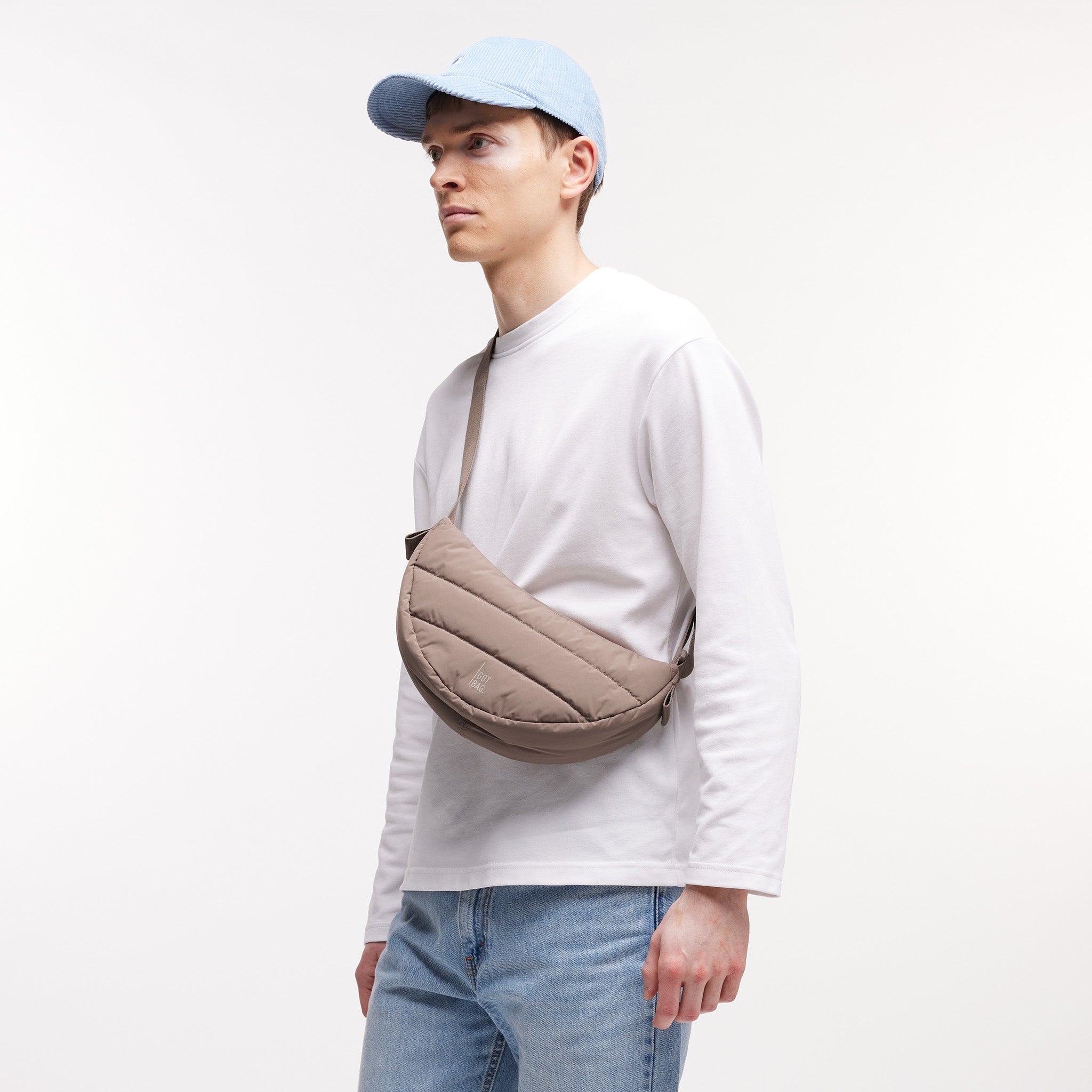 PUFFER MOON BAG SMALL Tasche in oyster (klassisches Taupe-Braun) von einem Mann crossbody getragen.