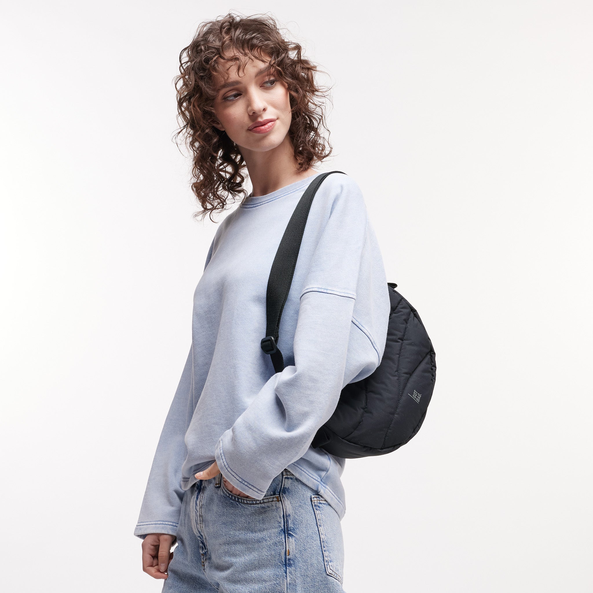 WAVY PUFFER MOON BAG Tasche in black (Schwarz) von einer Frau über der Schulter getragen.