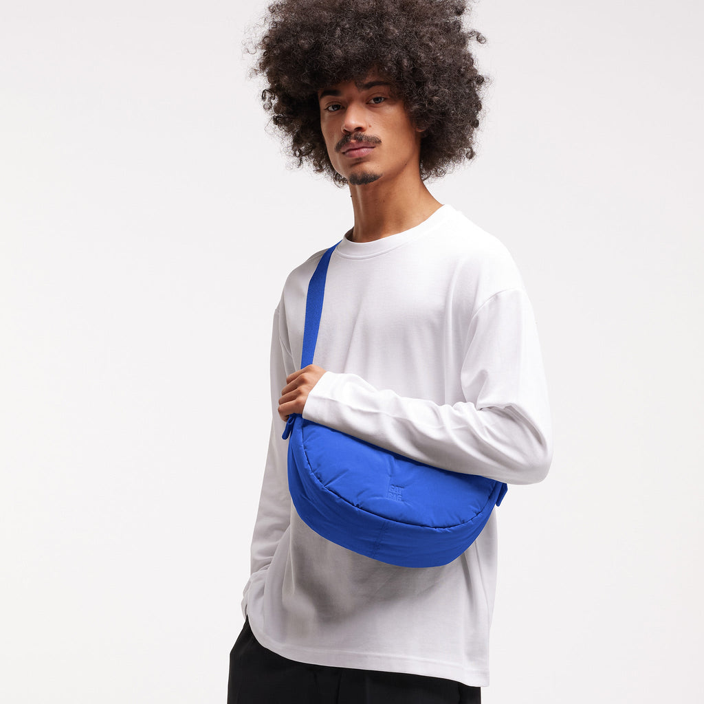 CLOUD MOON BAG SMALL Tasche in cobalt (leuchtendes Kobaltblau) von einem Mann crossbody getragen.