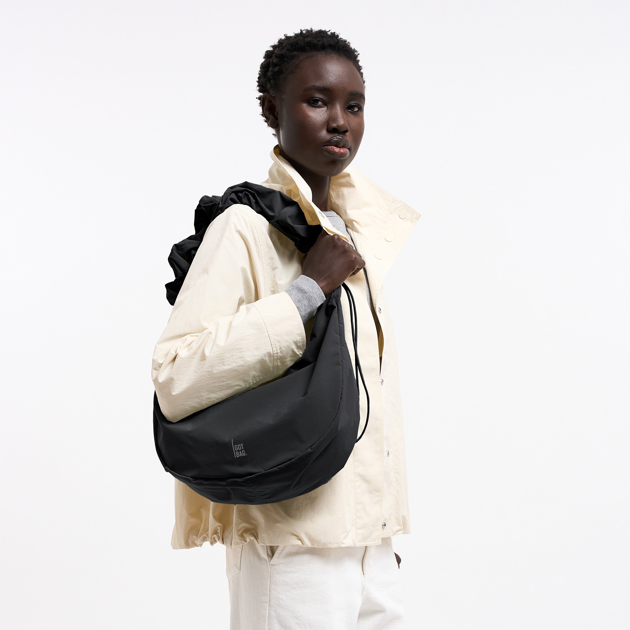 MOON BAG RUFFLE Tasche in black (Schwarz) von einer Frau über der Schulter getragen.