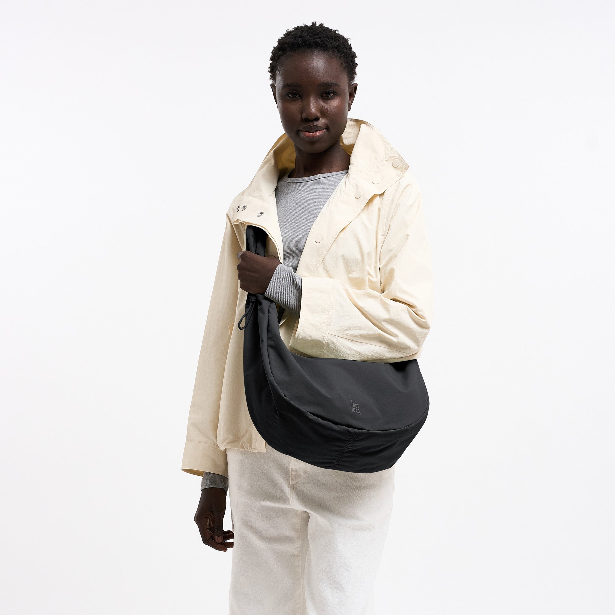 MOON BAG RUFFLE Tasche in black (Schwarz) von einer Frau über der Schulter getragen.