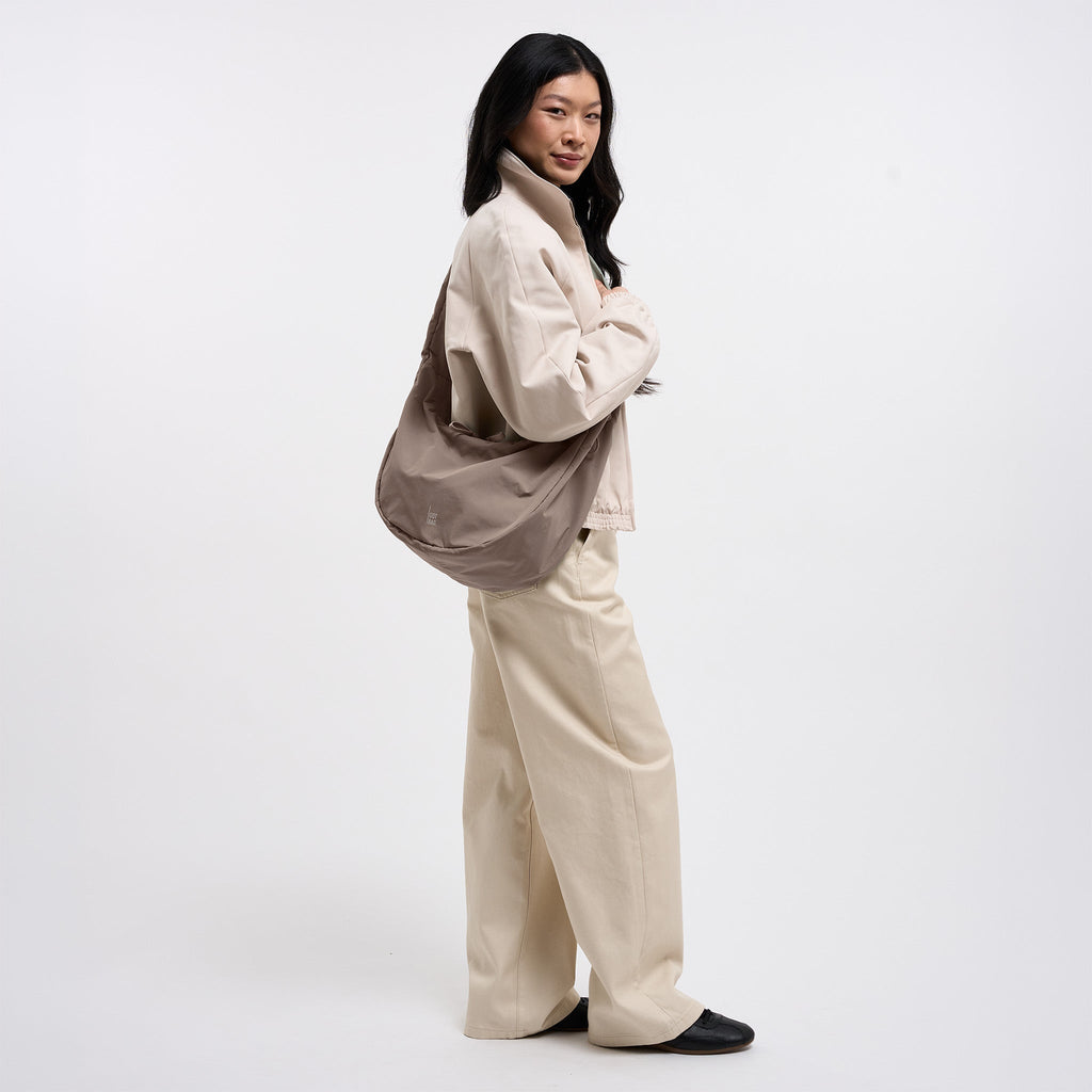 MOON BAG RUFFLE Tasche in oyster (klassisches Taupe-Braun) von einer Frau crossbody getragen.