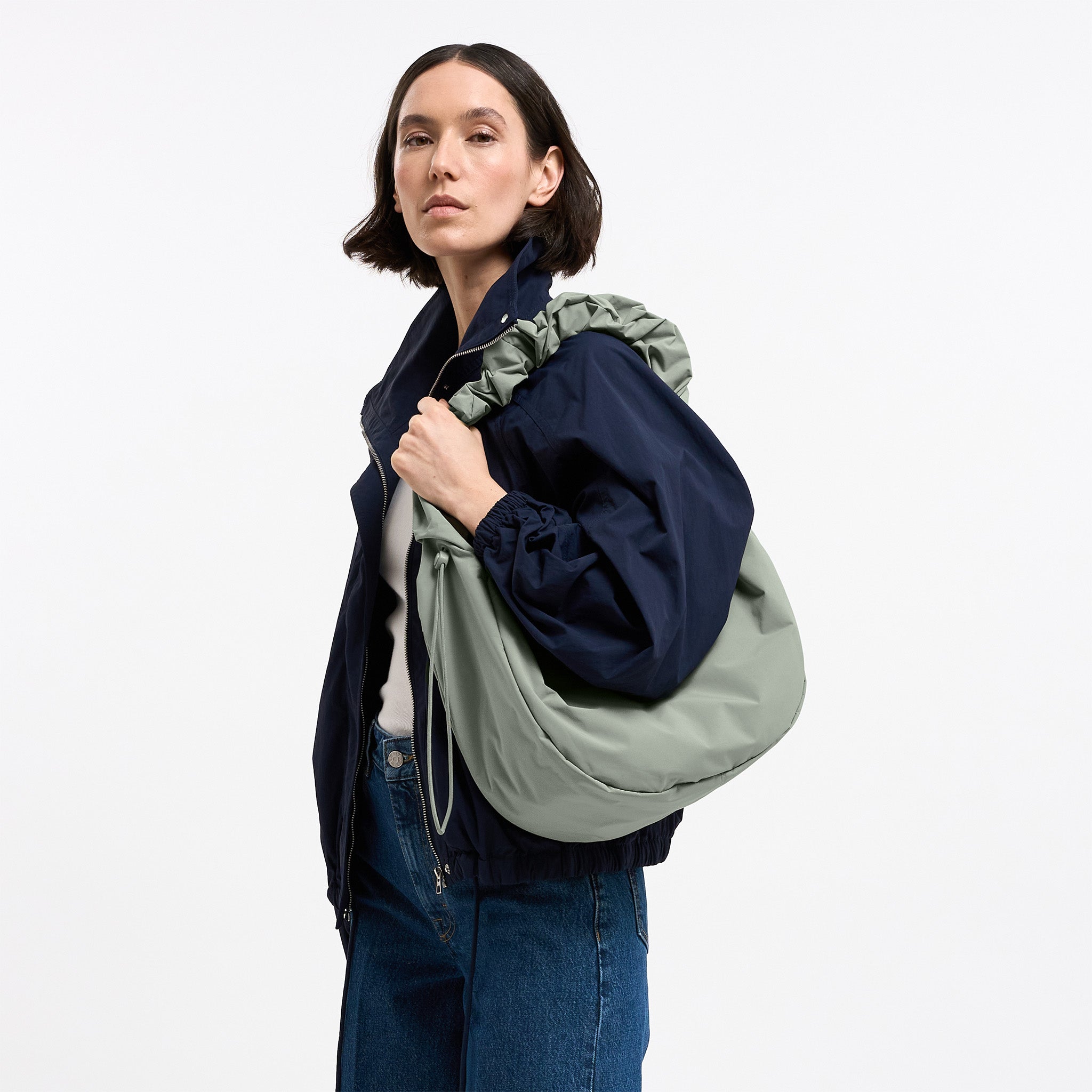 MOON BAG RUFFLE Tasche in bass (Salbeigrün) von einer Frau über der Schulter getragen.