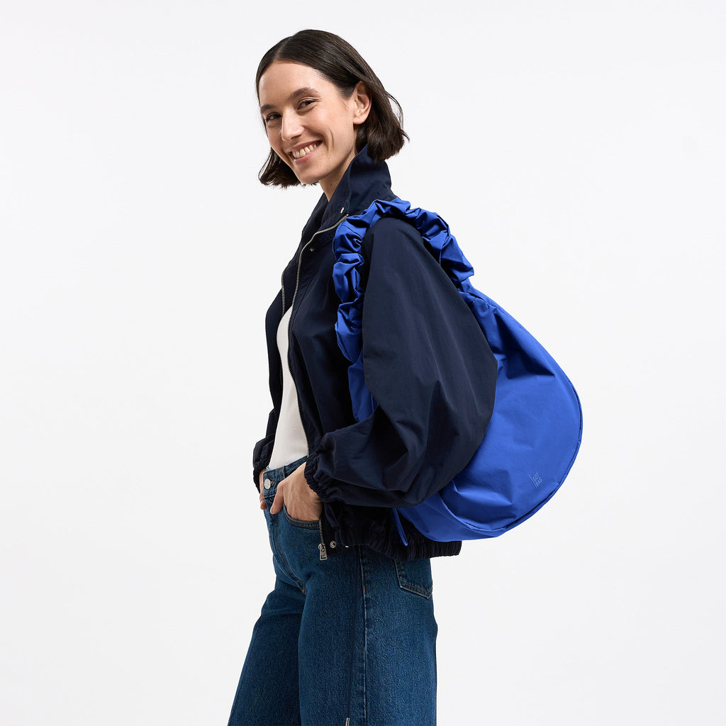 MOON BAG RUFFLE Tasche in cobalt (leuchtendes Kobaltblau) von einer Frau über der Schulter getragen.
