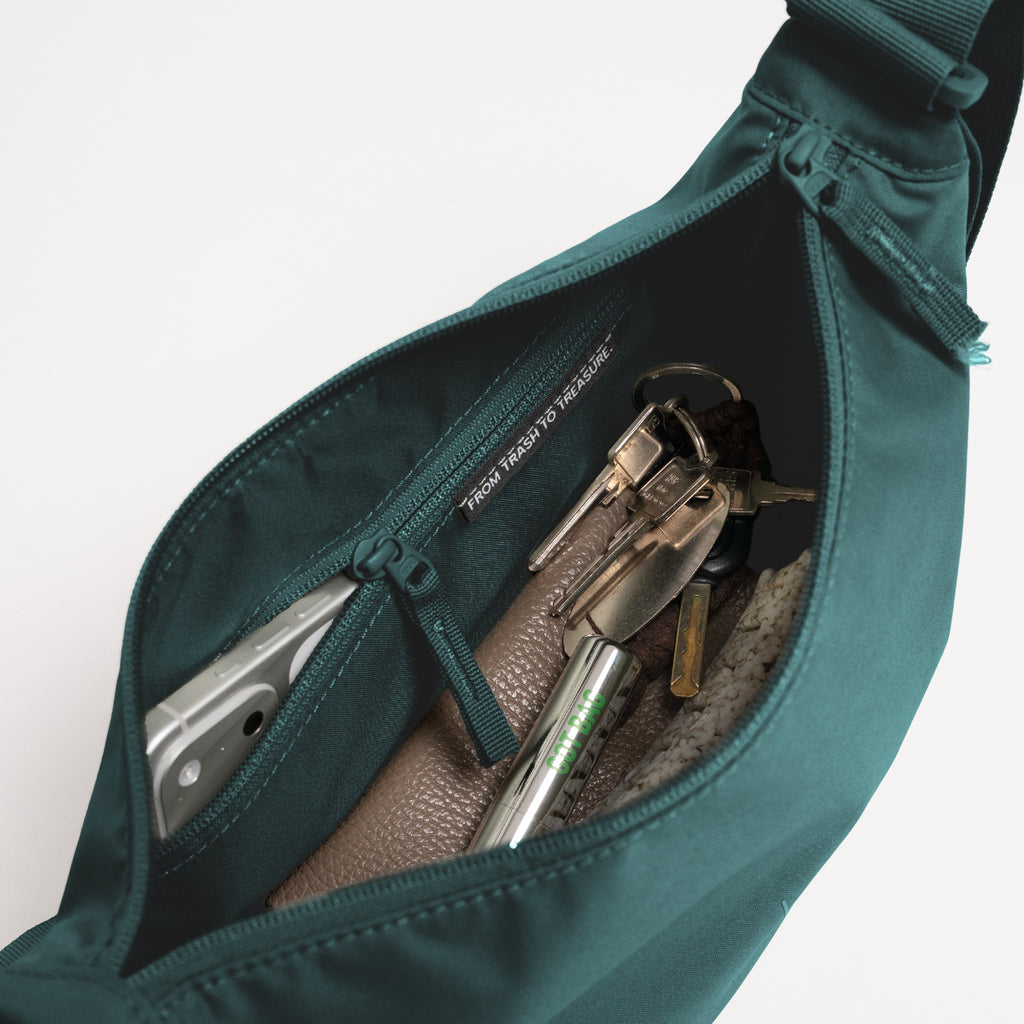 MOON BAG Tasche in sea teal (kühles Türkisgrün) mit Blick ins Innere und Gegenständen.