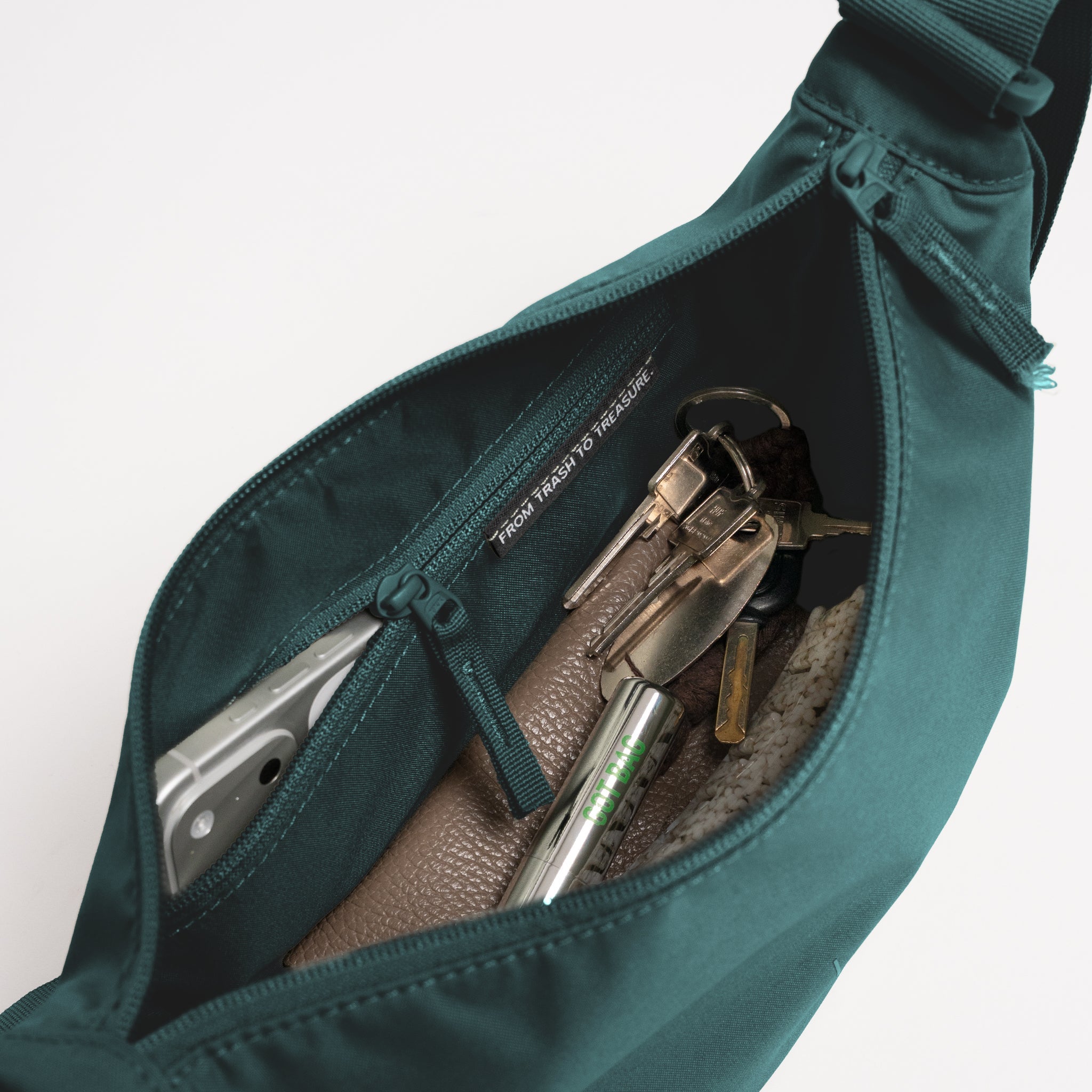 MOON BAG Tasche in sea teal (kühles Türkisgrün) mit Blick ins Innere und Gegenständen.