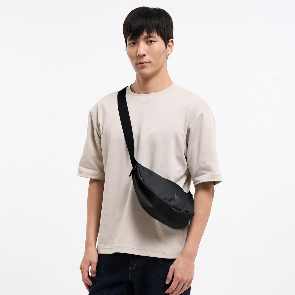 MOON BAG SMALL MONOCHROME Tasche in black (Schwarz) von einem Mann crossbody getragen.