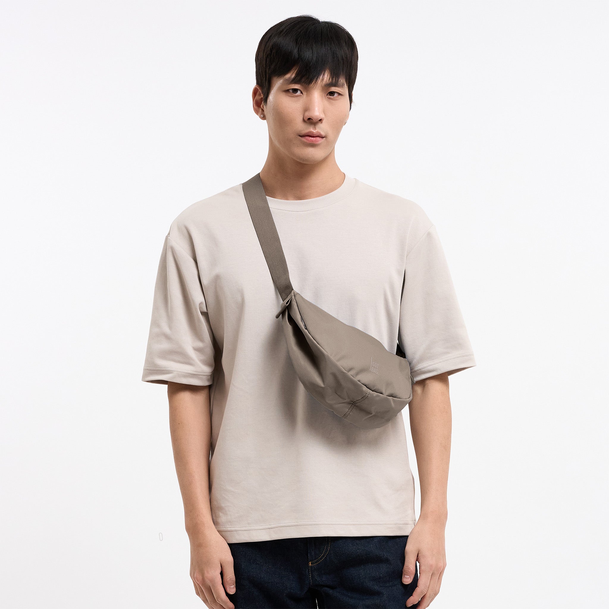 MOON BAG SMALL MONOCHROME Tasche in seal (dunkler Beigeton) von einem Mann crossbody getragen.