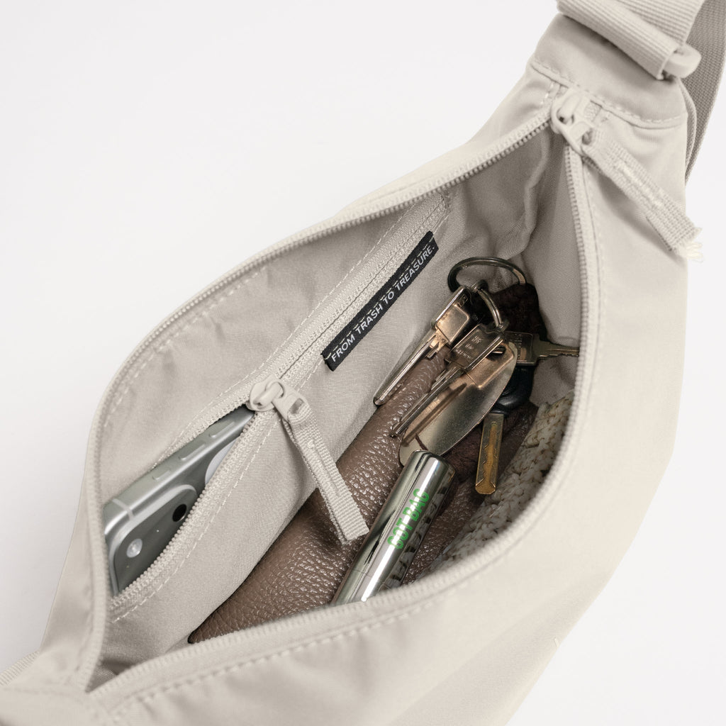 MOON BAG SMALL MONOCHROME Tasche in soft shell (warmes Cremeweiß) als Detailaufnahme von innen mit Inhalt.