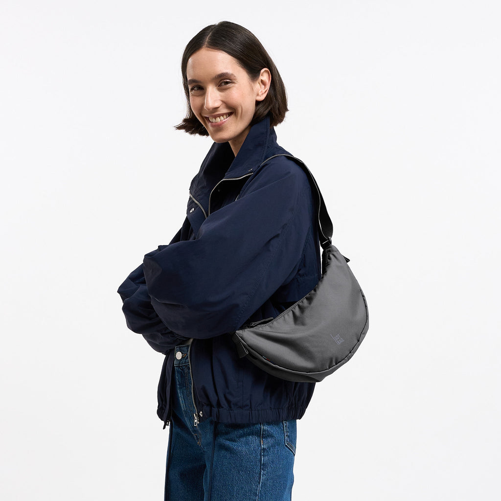 MOON BAG SMALL Tasche in shark (Dunkelgrau) von einer Frau crossbody getragen.