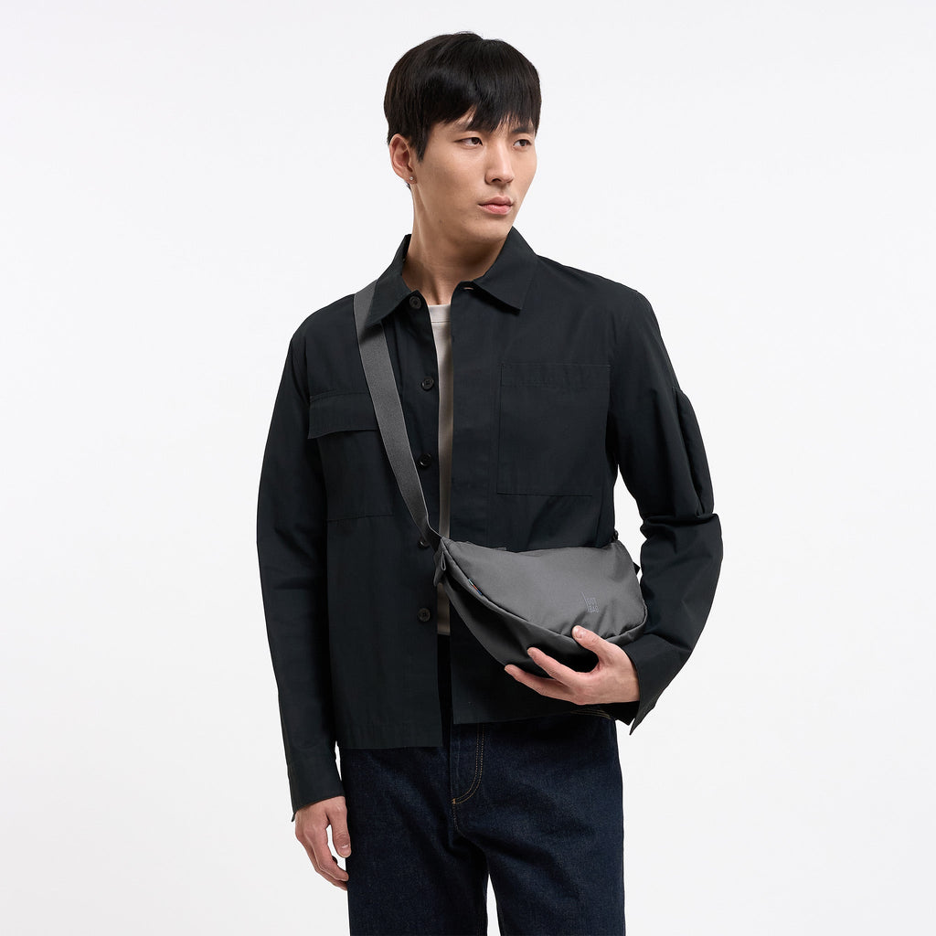 MOON BAG SMALL Tasche in shark (Dunkelgrau) von einem Mann crossbody getragen.