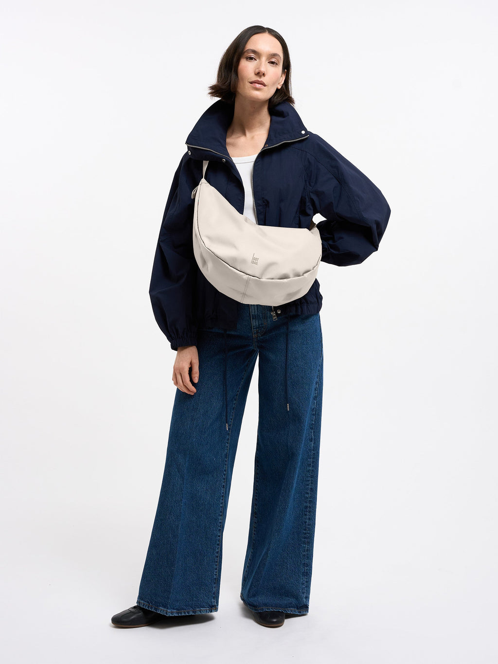 MOON BAG LARGE Tasche in soft shell (warmes Cremeweiß) von einer Frau crossbody getragen.