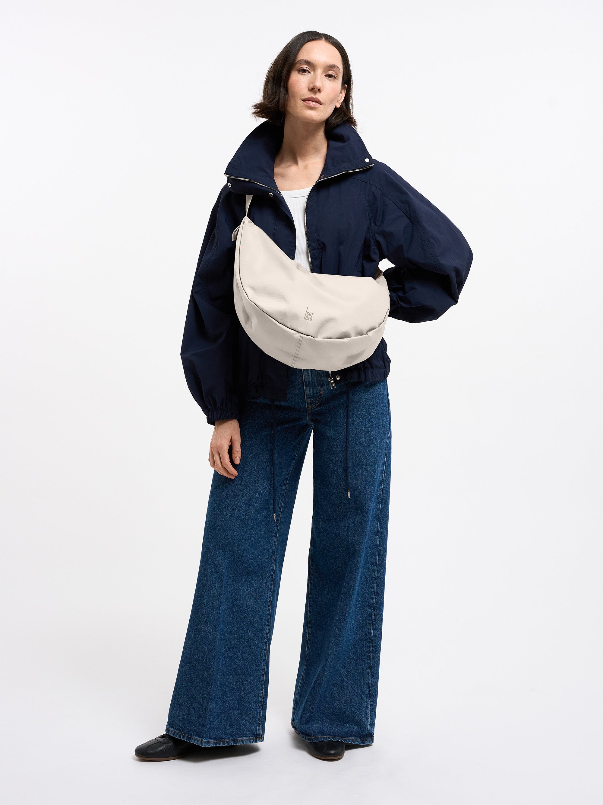 MOON BAG LARGE Tasche in soft shell (warmes Cremeweiß) von einer Frau crossbody getragen.