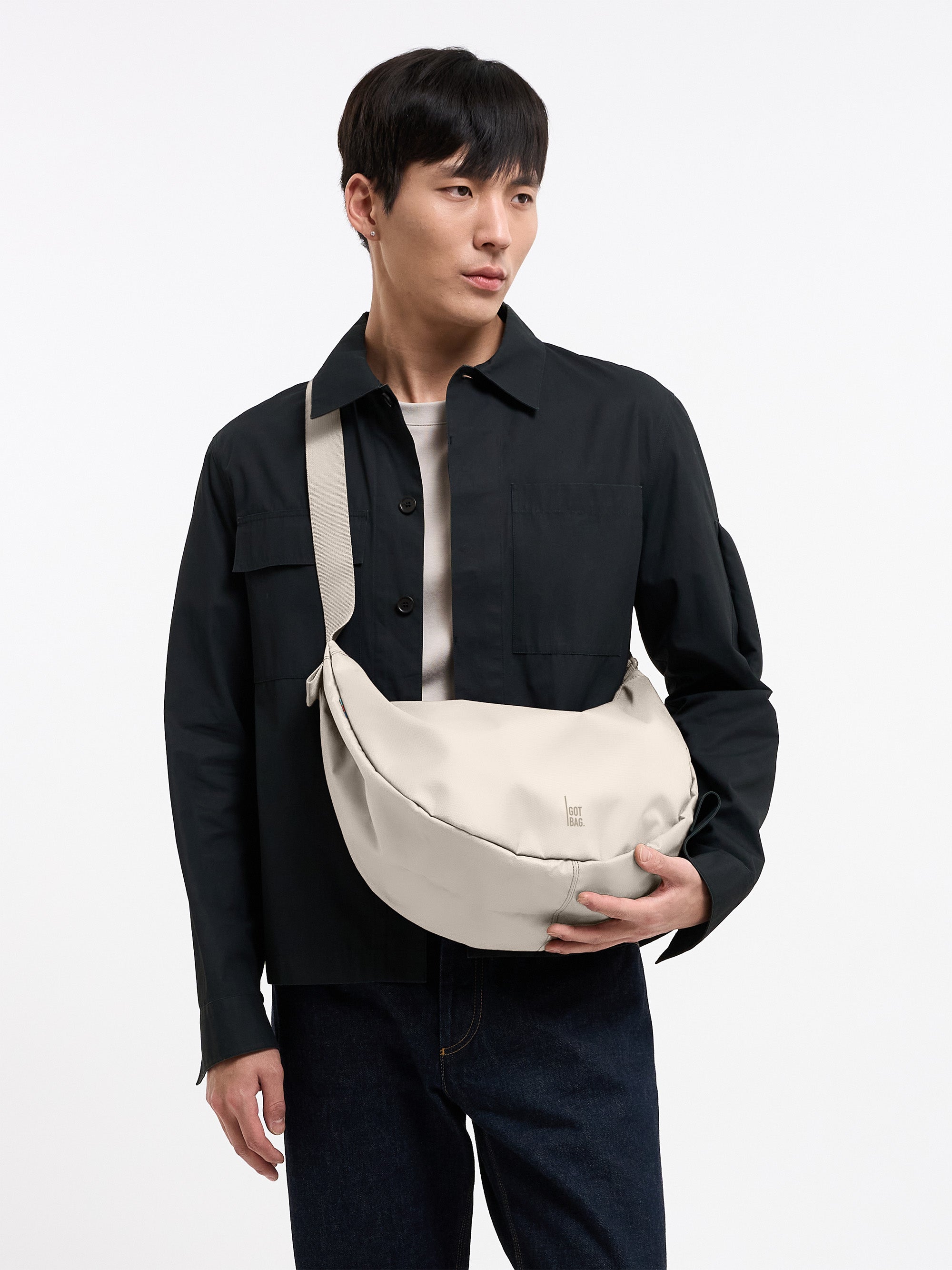 MOON BAG LARGE Tasche in soft shell (warmes Cremeweiß) von einem Mann crossbody getragen.