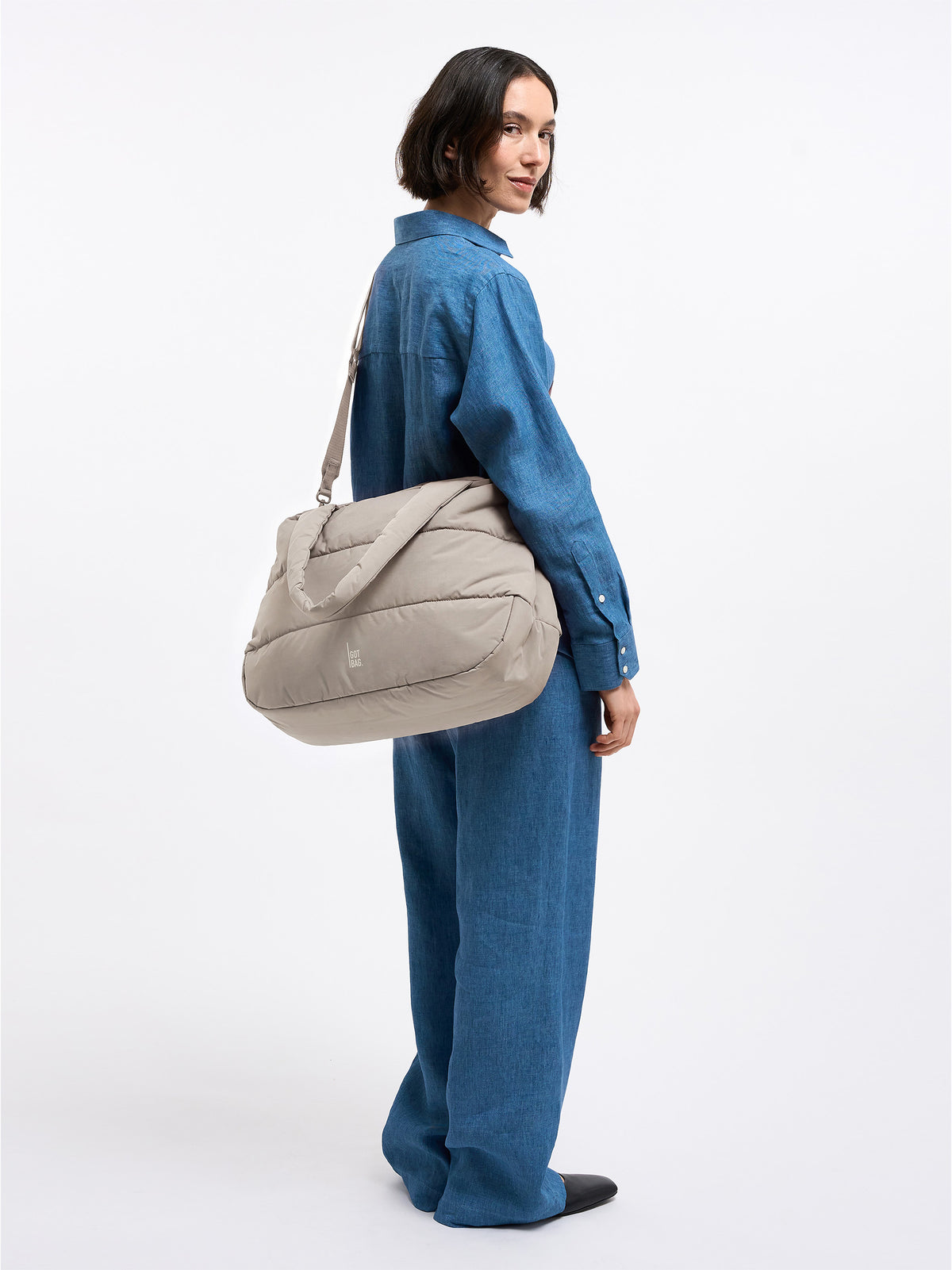 PUFFER HORIZON TOTE BAG Tasche in scallop (helles Beige) von einer Frau über der Schulter getragen.