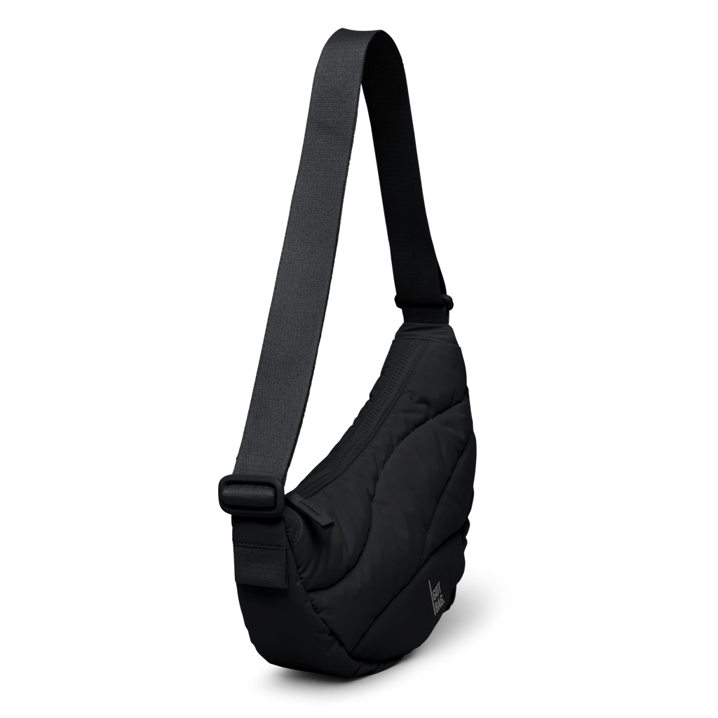 WAVY PUFFER MOON BAG Tasche in black (Schwarz) als Studioaufnahme in diagonaler Ansicht.